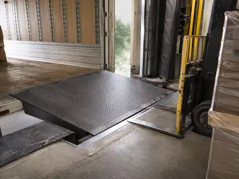 Industrial dock leveler bridging the warehouse loading dock and trailer floor
