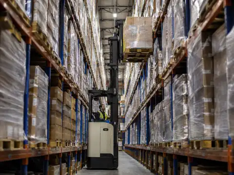 Narrow-aisle reach forklift lifting a pallet between high warehouse racks
